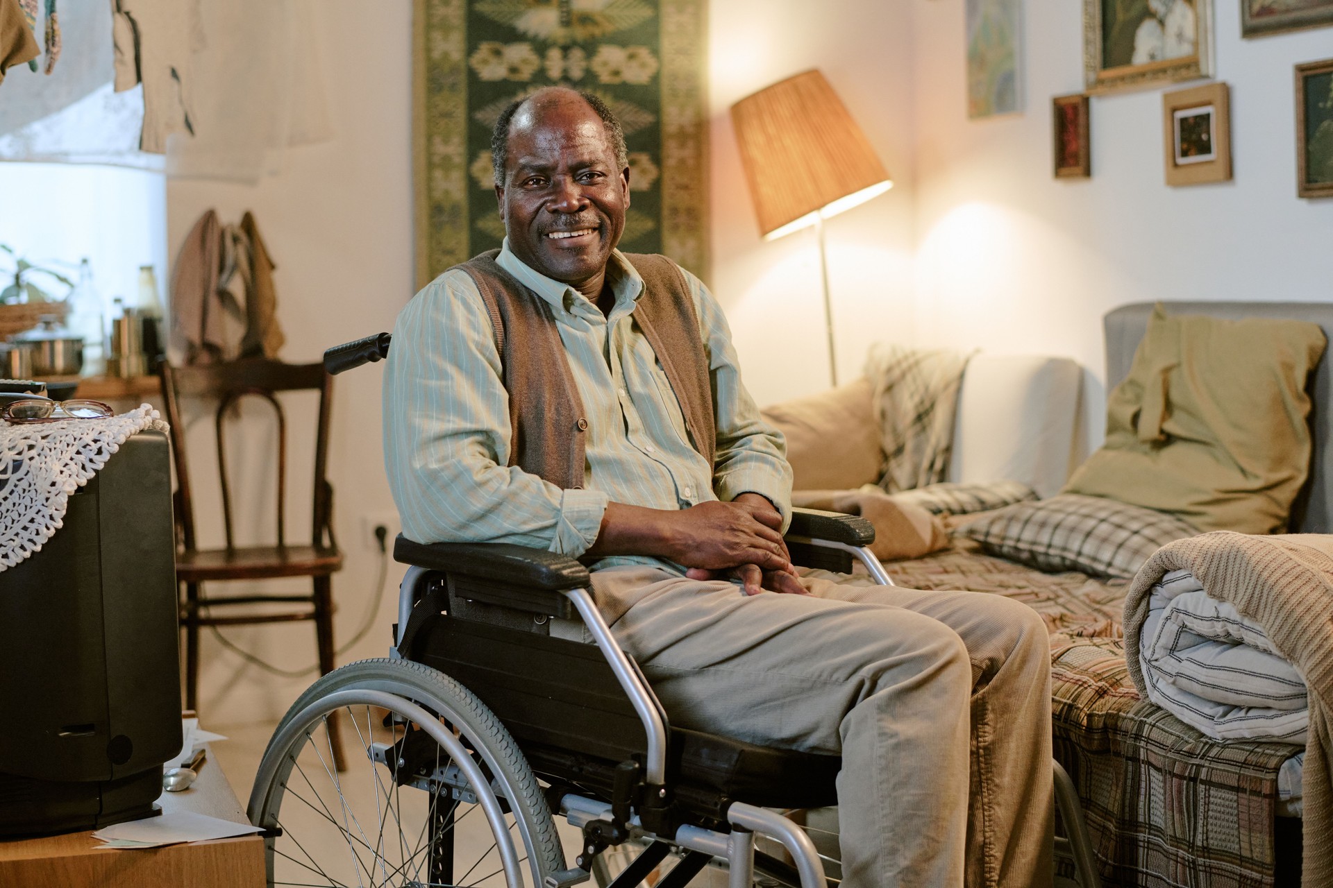 Portrait of Senior Black Man Sitting in Wheelchair Smiling in Modest Home